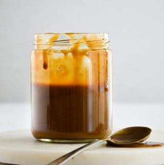 Vegan Salted Caramel in a mason jar with caramel dripping from the top and a spoon to the side with caramel on it