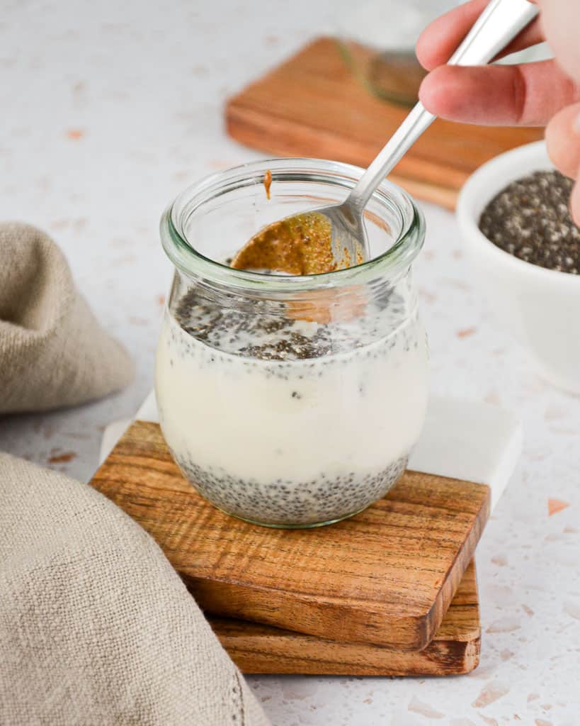 stirring a peanut butter covered spoon into chia pudding