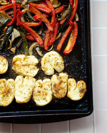close up of roasted halloumi on a sheet pan with roasted peppers and onions