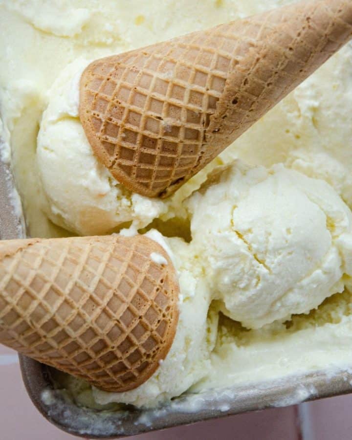 coconut pineapple ice cream in a loaf pan with two ice cream cones