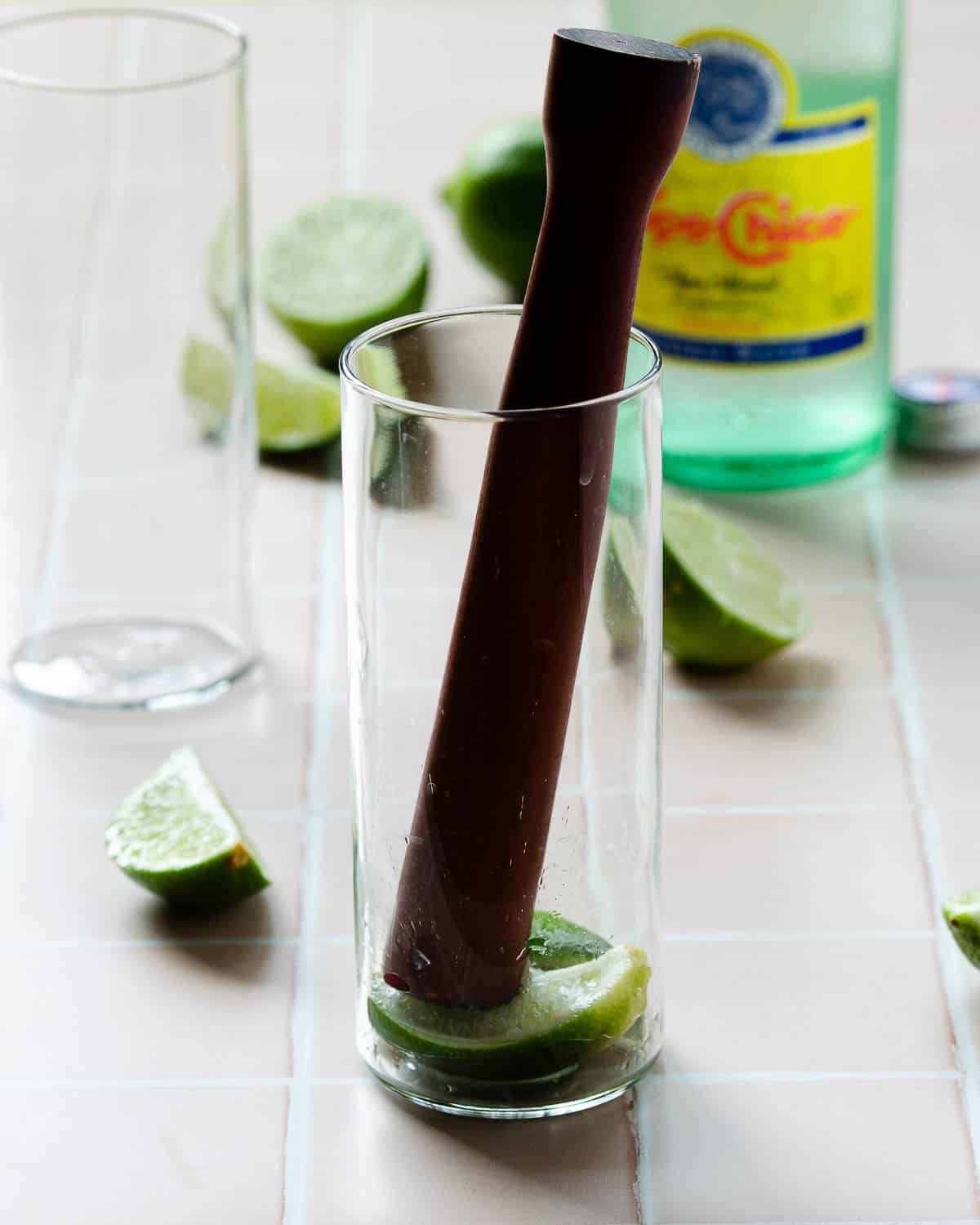 Muddling limes in a glass. 