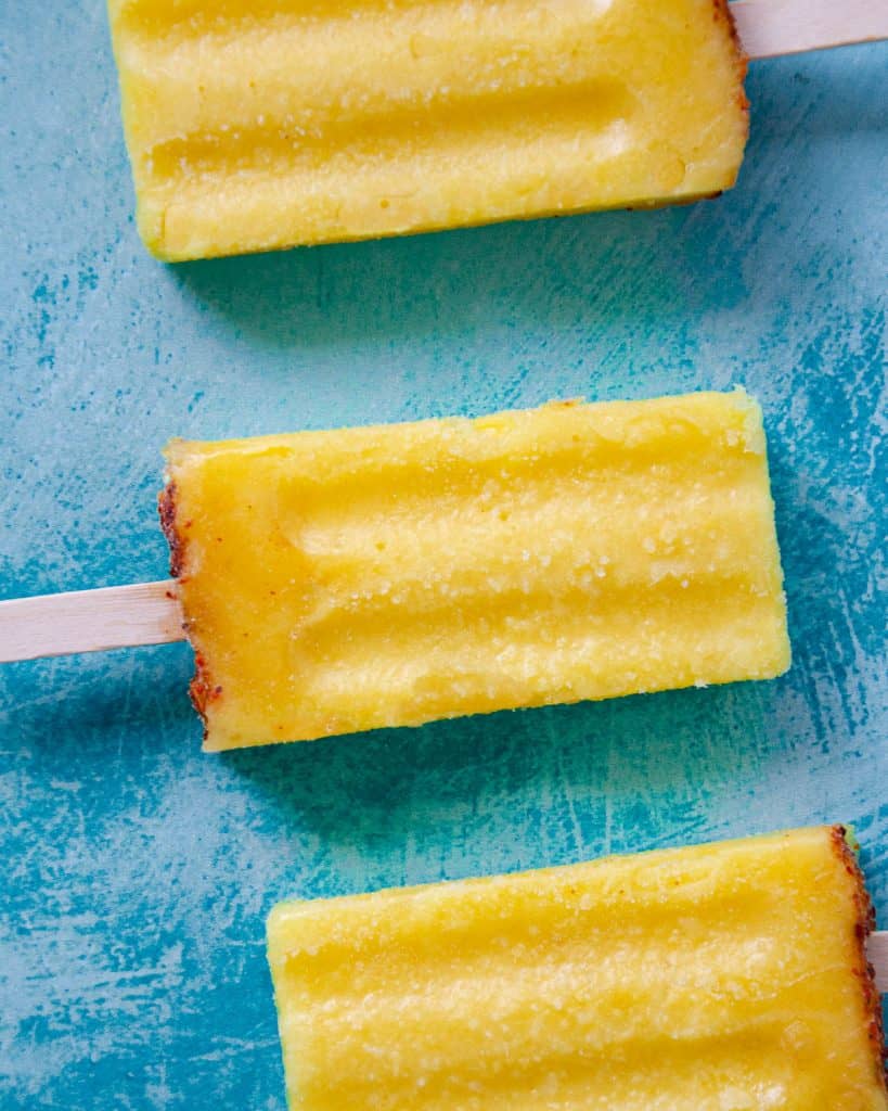 three mango pineapple popsicles in a line