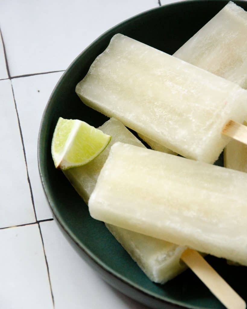 angled photo of popsicles on a plate with lime wedges