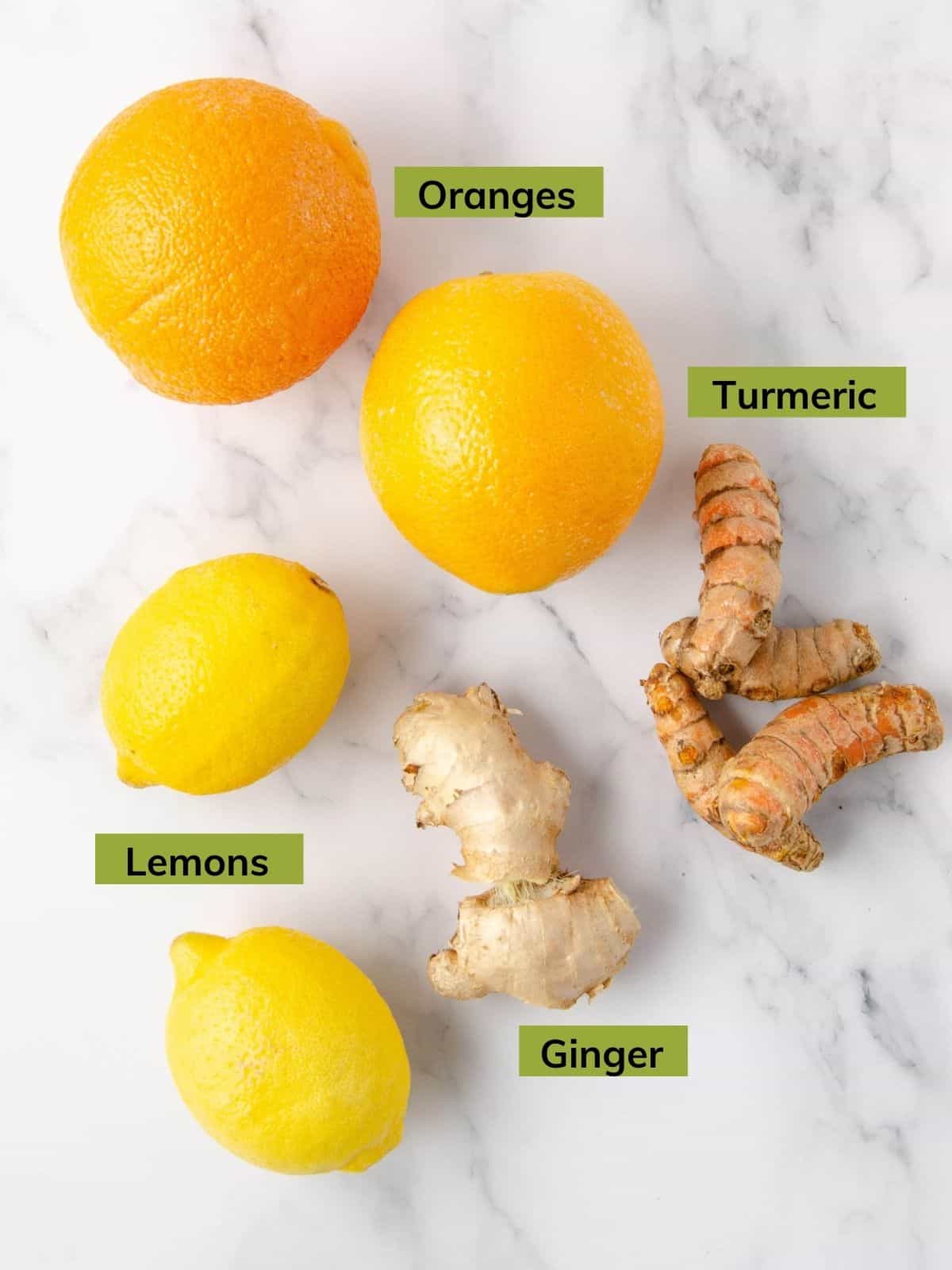 ingredients for a turmeric shot: two oranges, two lemons, two pieces of ginger and two pieces of turmeric.