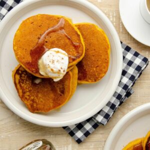 Featured image of three pumpkin pancakes on a plate.