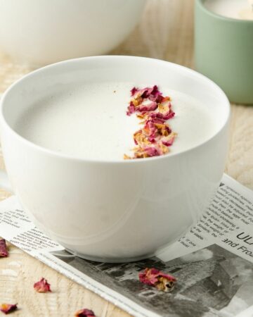 A featured image of a rose tea latte topped with rose petals.