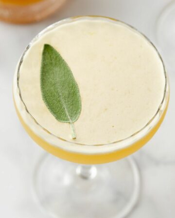 Featured image of close up of a sage leaf atop a bee's knees cocktail.