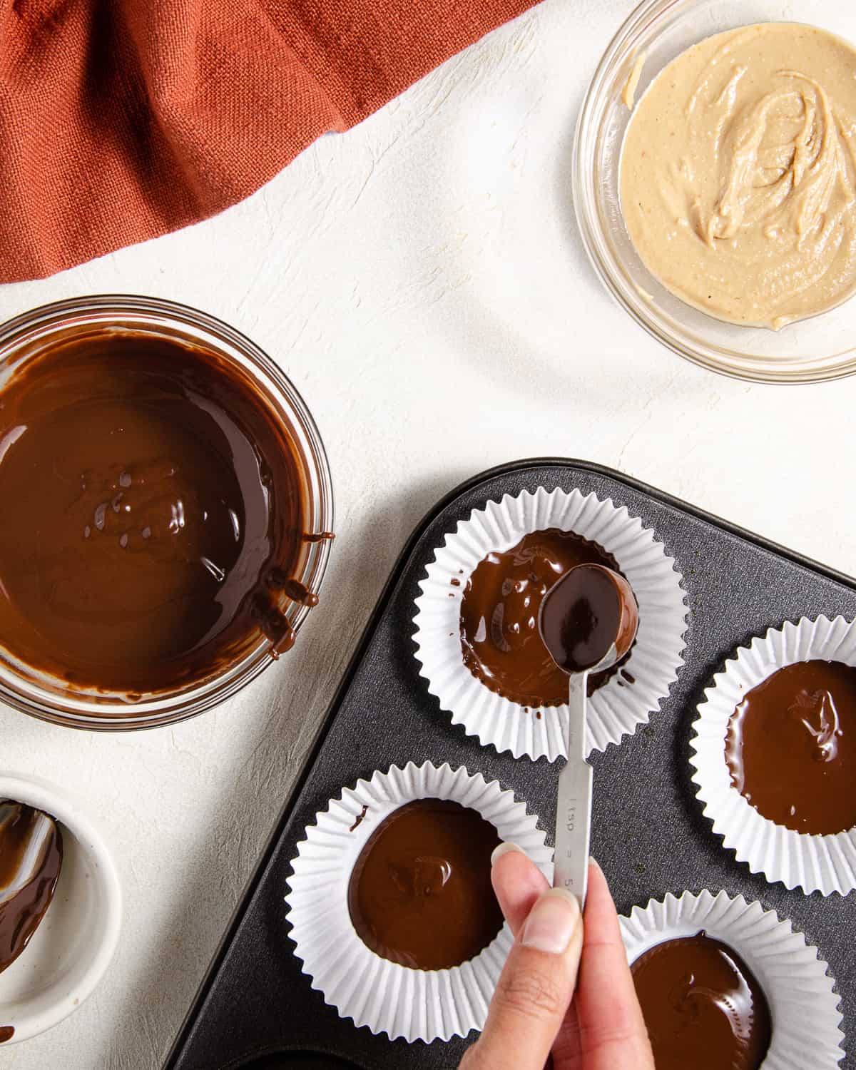 Pouring melted chocolate into muffin tin liners.