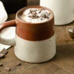 A close up view of a burgundy mug filled with hot cocoa.