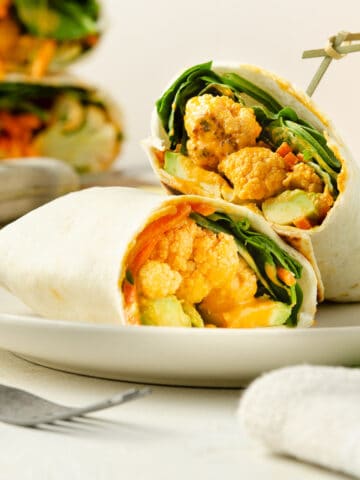 A close up view of a wrap split in half, able to see the roasted cauliflower.