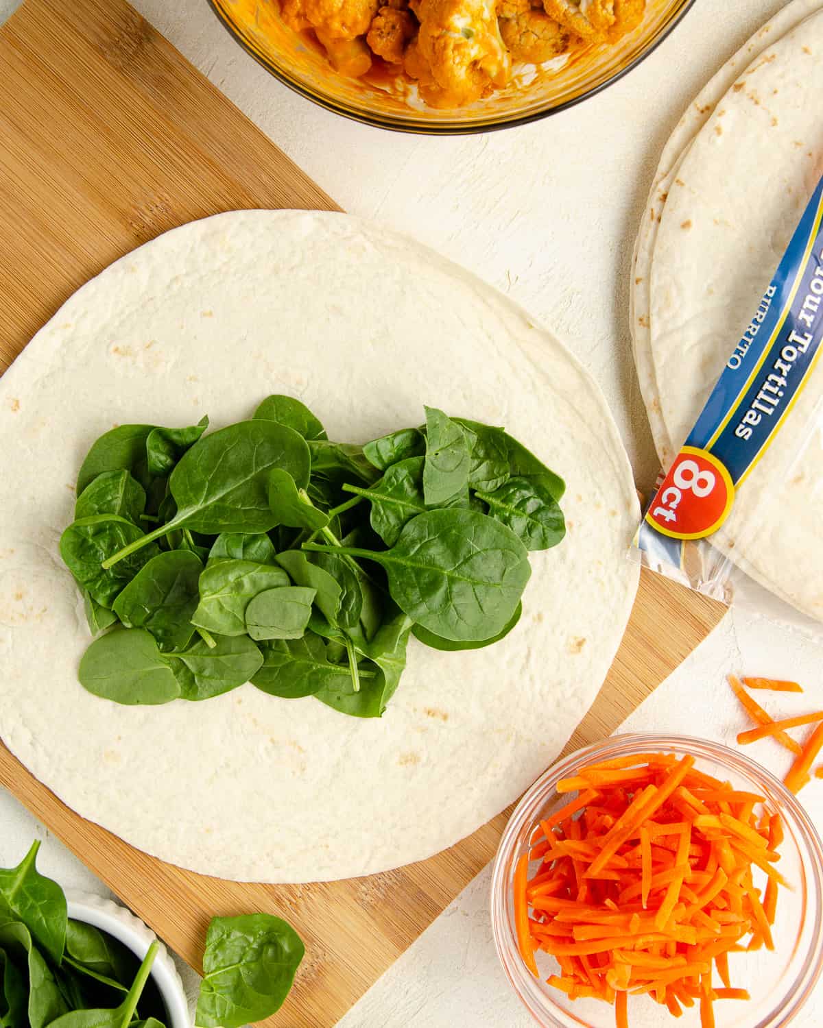 Step one of making the wrap: adding spinach on top of the tortilla.