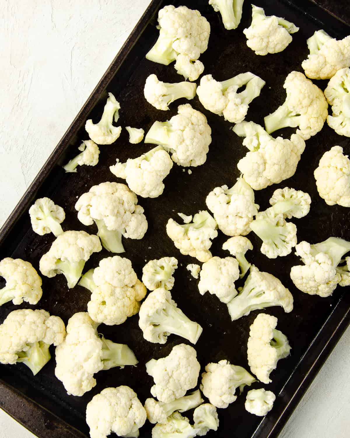 Cauliflower florets on a baking sheet ready to roast.