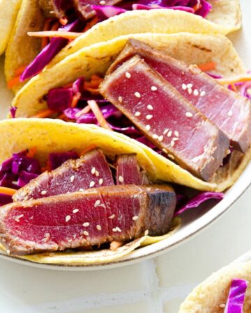 Featured image of a plate of ahi tuna tacos on top of a cabbage slaw.