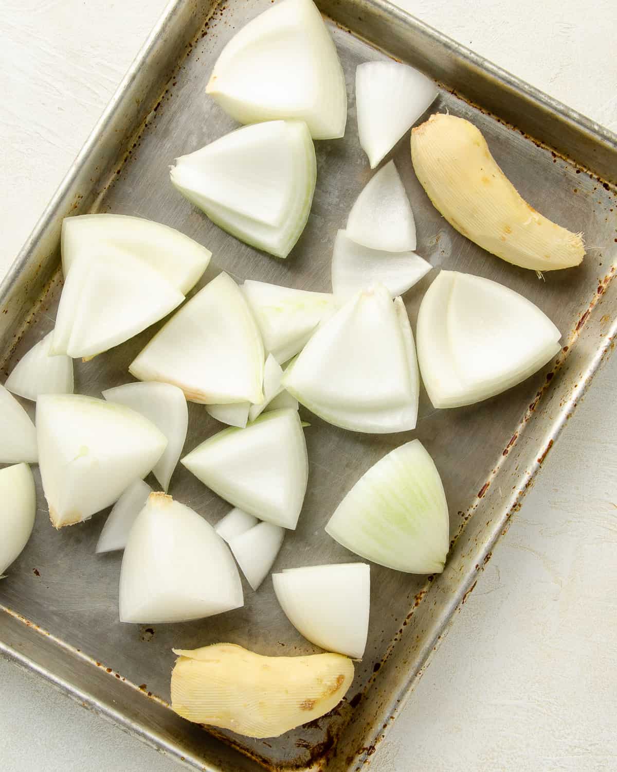 Chopped onions and ginger root on a sheet tray to broil. This helps give flavor to the broth.