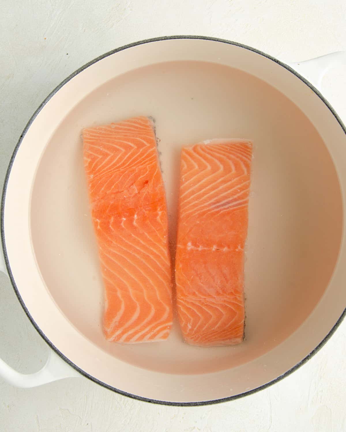 Salmon filets brining in a pot of cold water and salt.