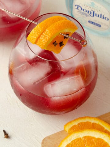Close up view of a skinny cranberry margarita garnished with oranges.