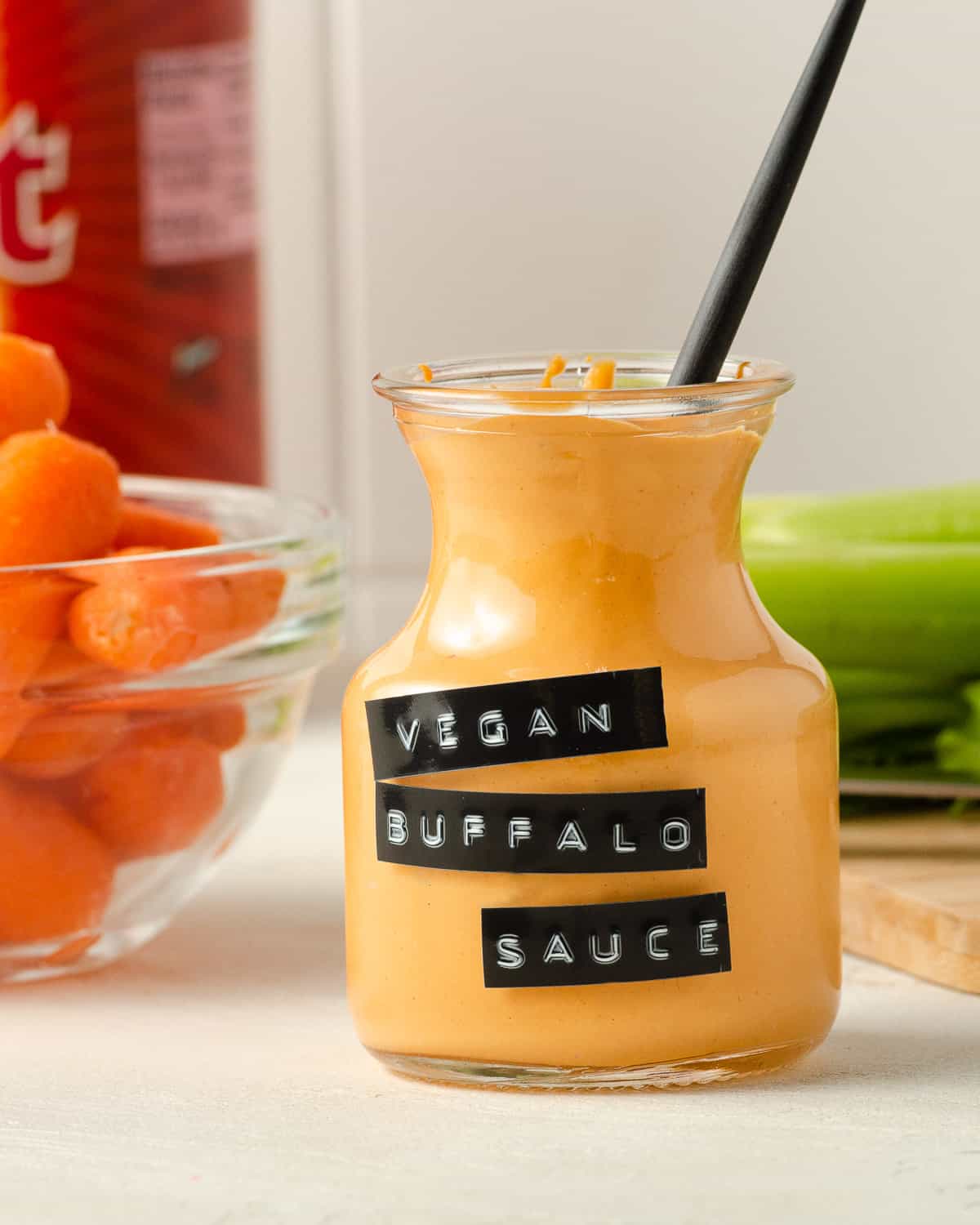 Straight on view of buffalo sauce in a jar with a spoon inside.
