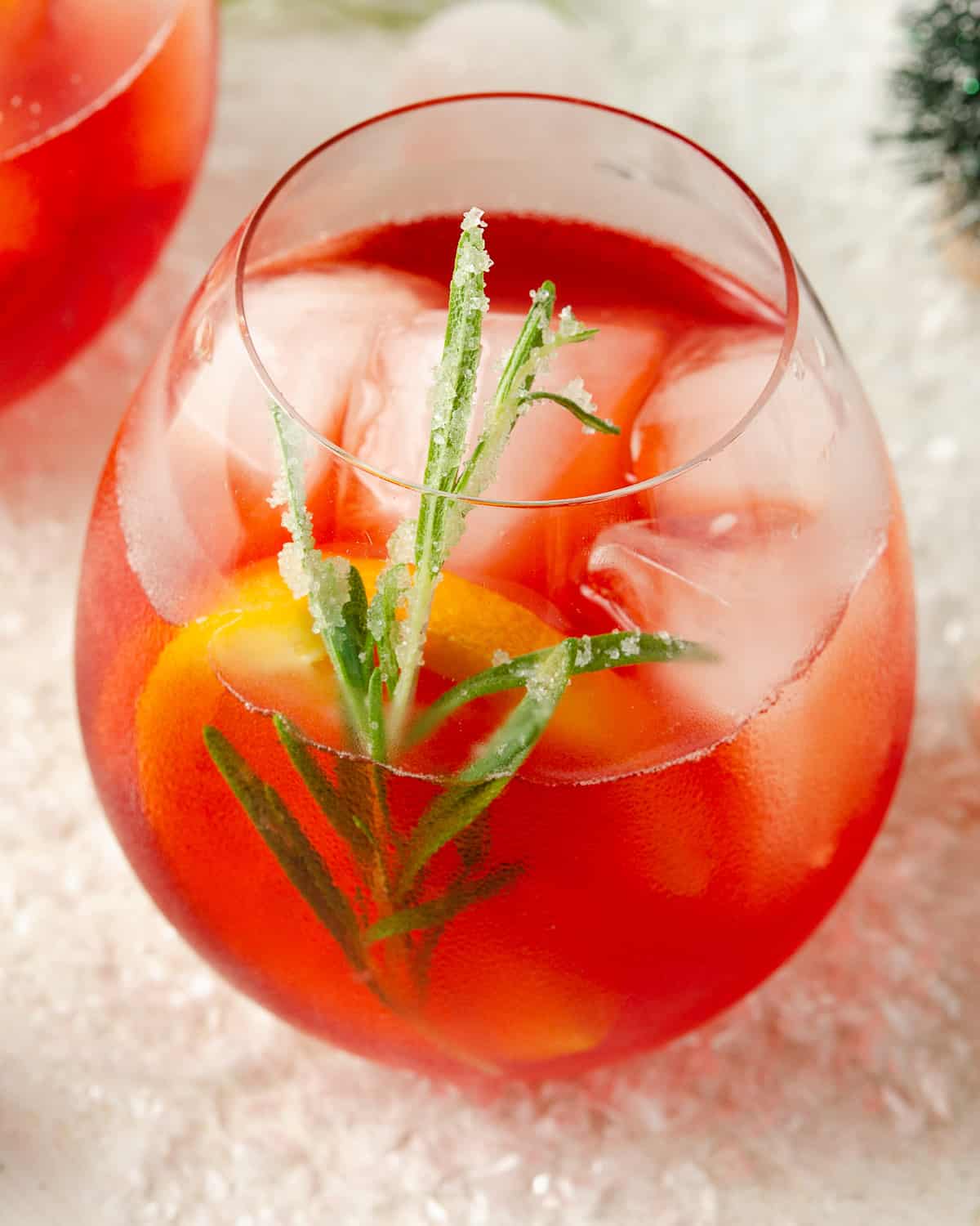 A close up of a sugared rosemary leaf in a Winter Aperol cocktail.