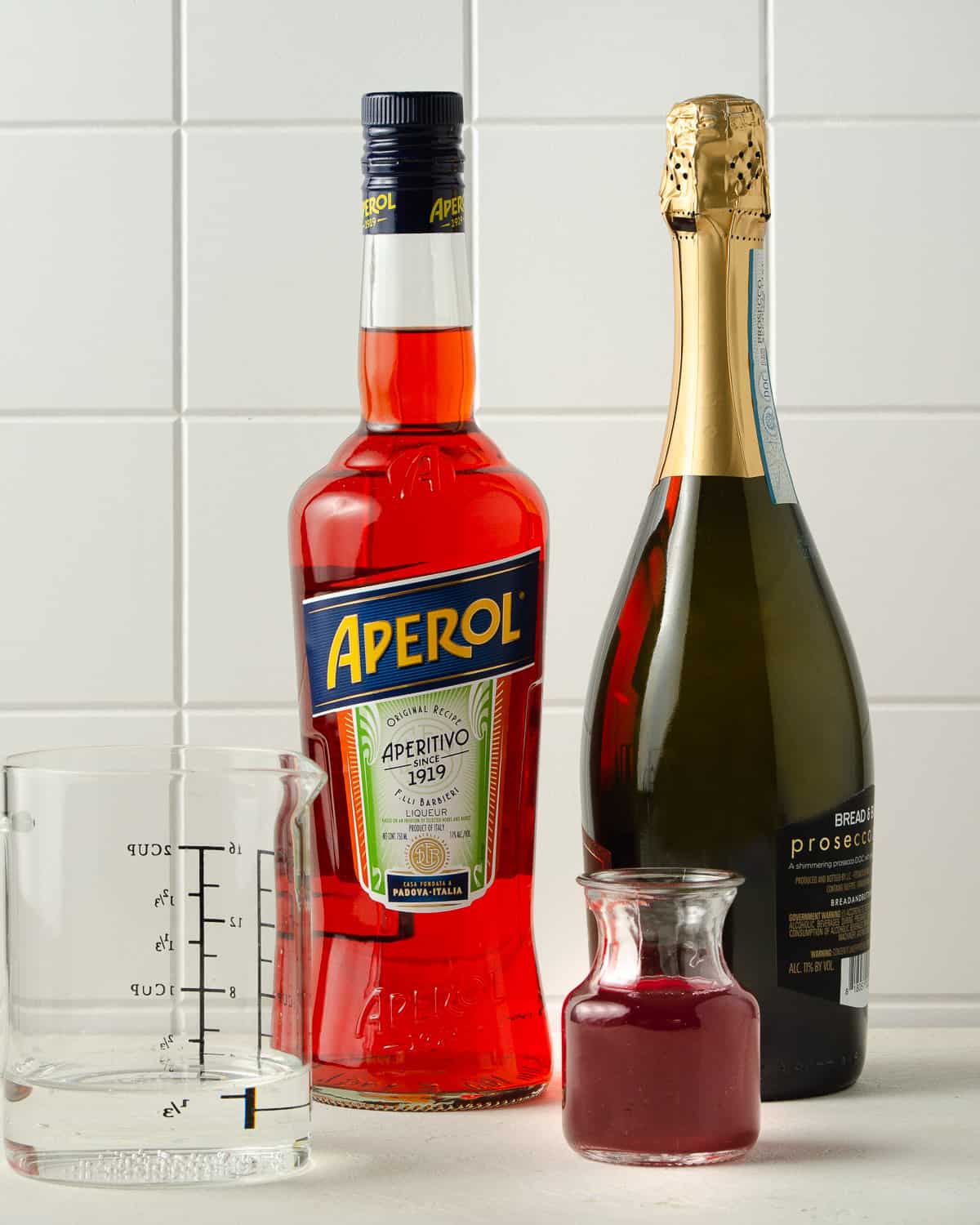 Ingredients for a Winter Aperol Spritz - Aperol, Prosecco, homemade cranberry simple syrup and club soda.