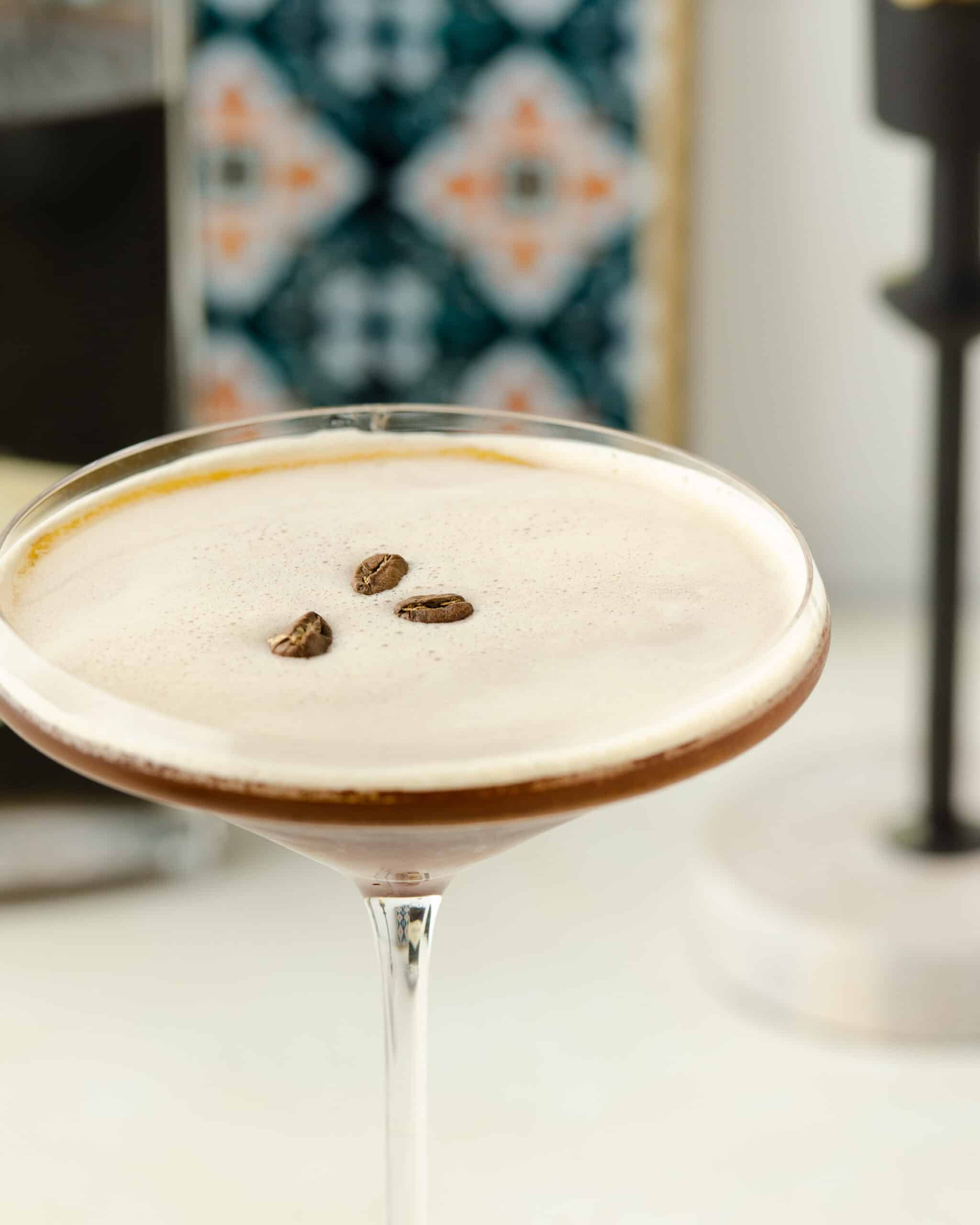 Up close shot of espresso martini in a cocktail glass with coffee beans.