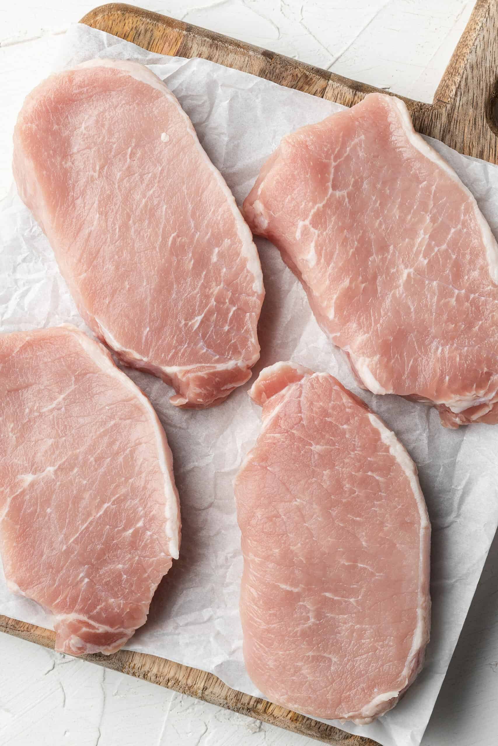 Raw pork chops on a cutting board.