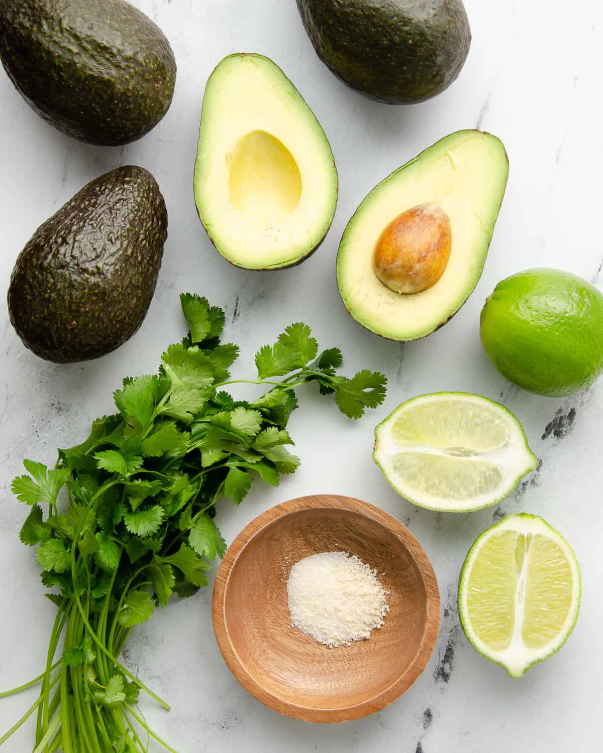 Ingredients needed to make 4 ingredient guacamole. Avocados, garlic salt, cilantro, and limes. 