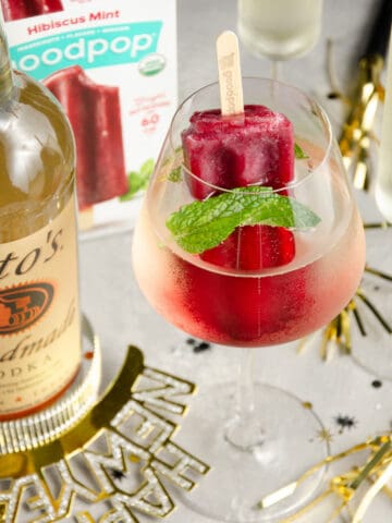 A featured image of popsicle in a wine glass filled with vodka.