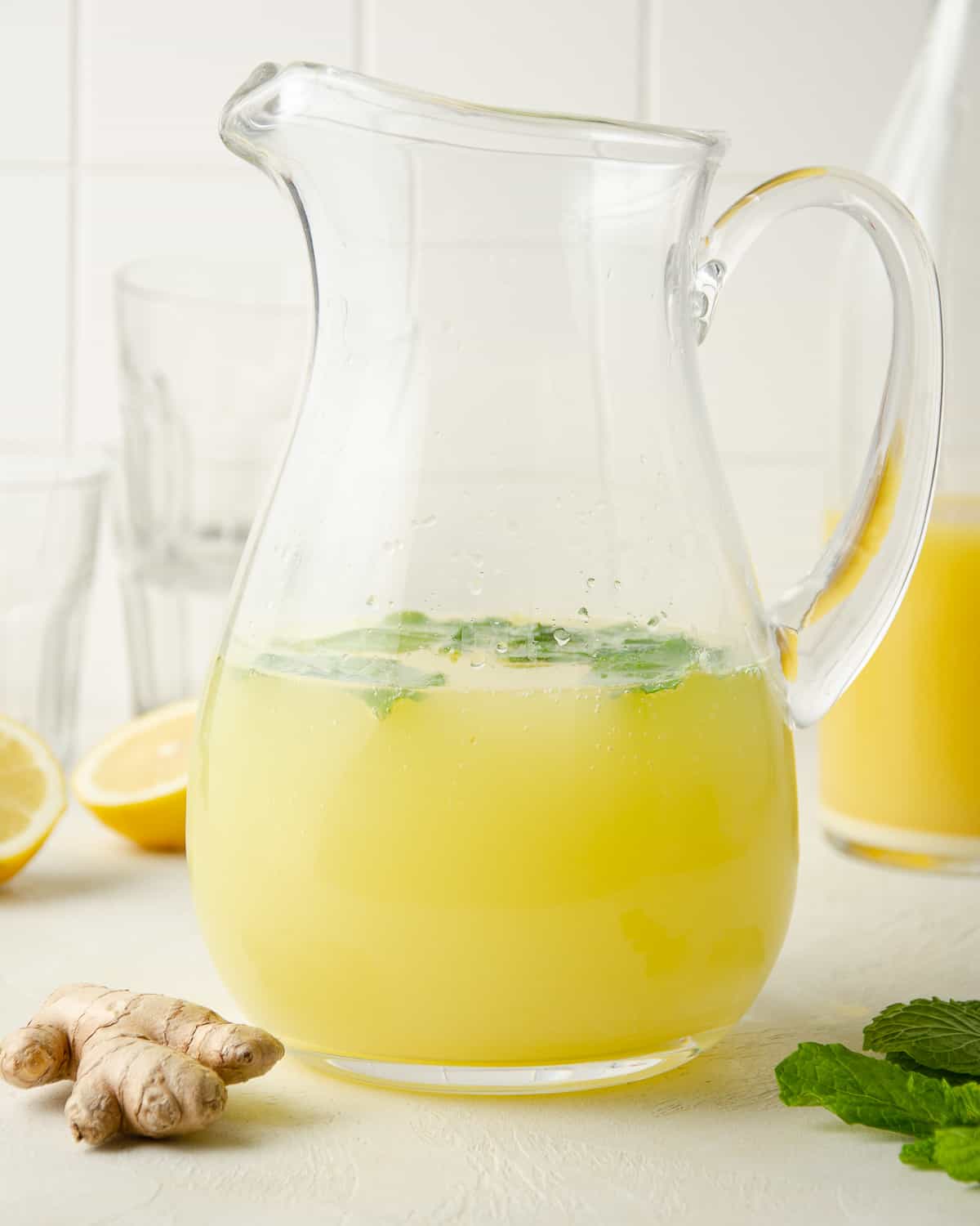 A glass pitcher of mint and ginger lemonade.