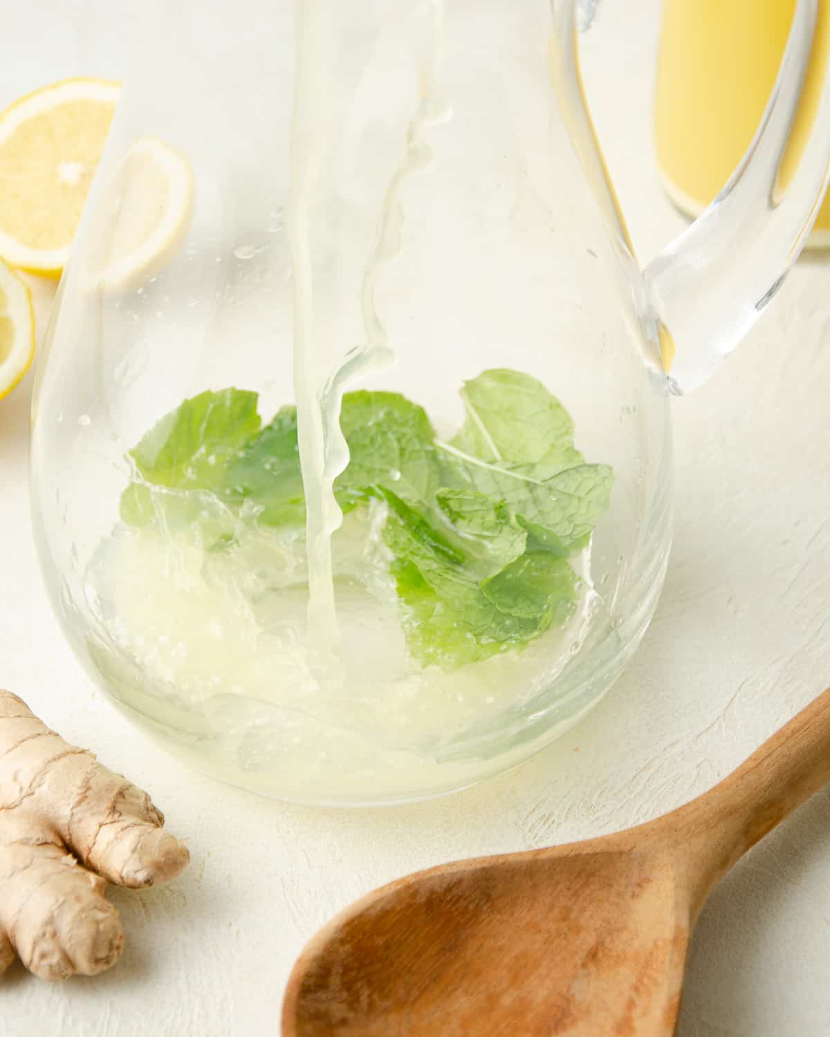 Adding fresh lemon juice to a glass pitcher.