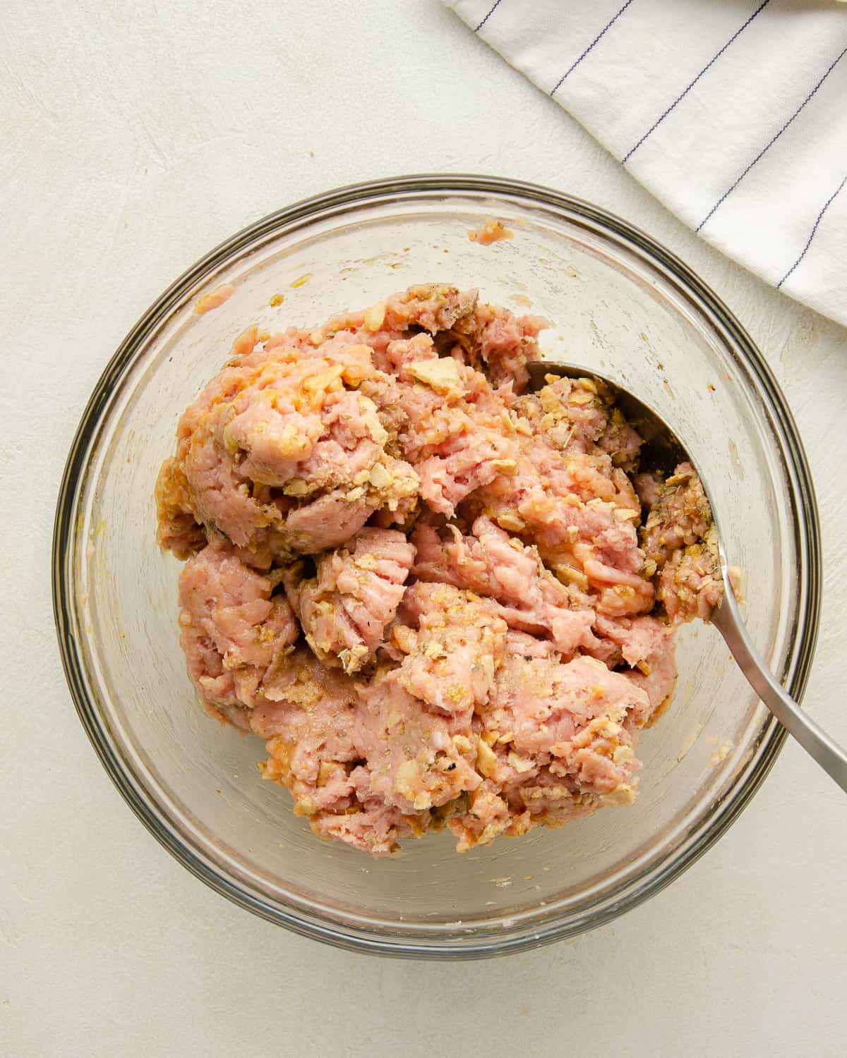 Ground turkey mixed with other ingredients for gluten free meatballs.