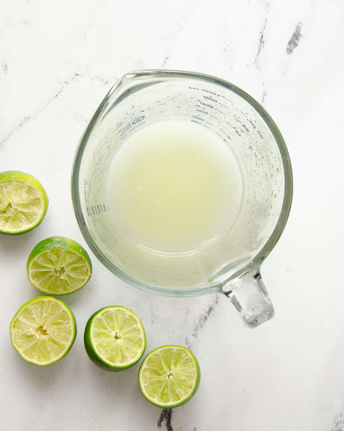 A large measuring cup filled with fresh squeezed lime juice.