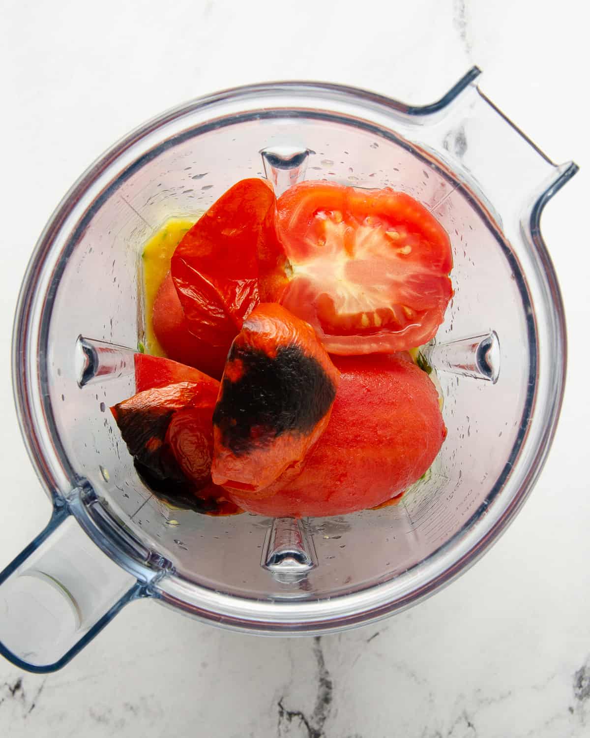 Adding roma tomatoes to the blender of pureed mango salsa.
