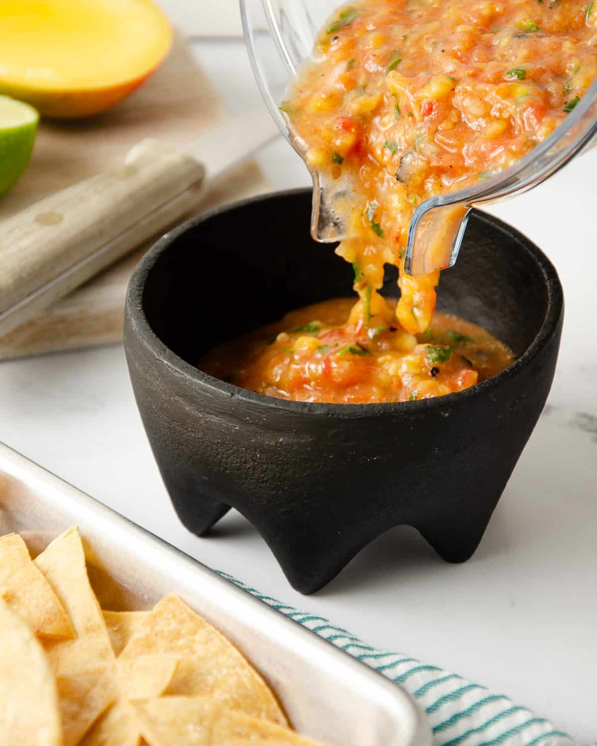 Pouring blended salsa into a molcajete.