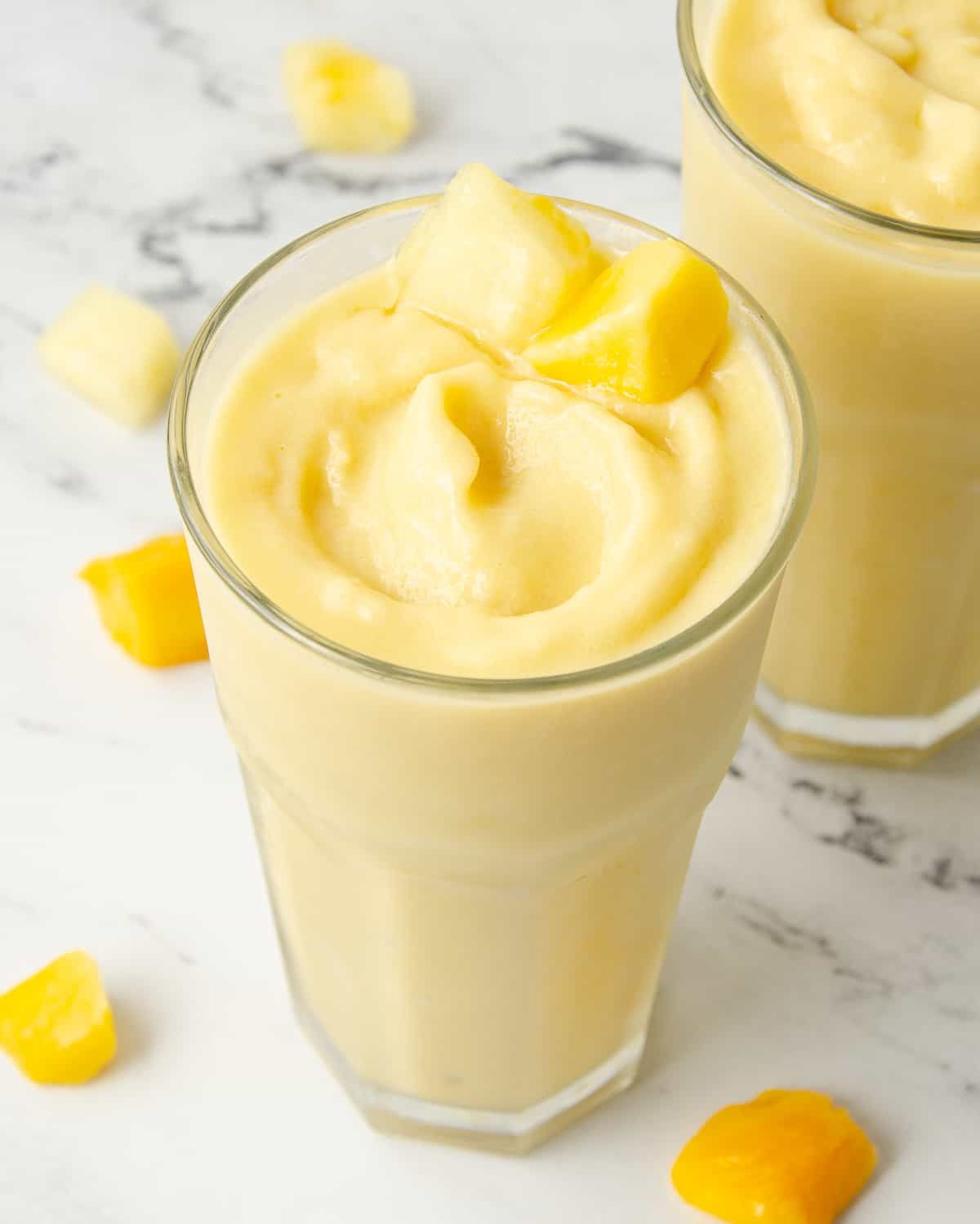 A glass of pineapple and mango smoothie swirled in a glass.