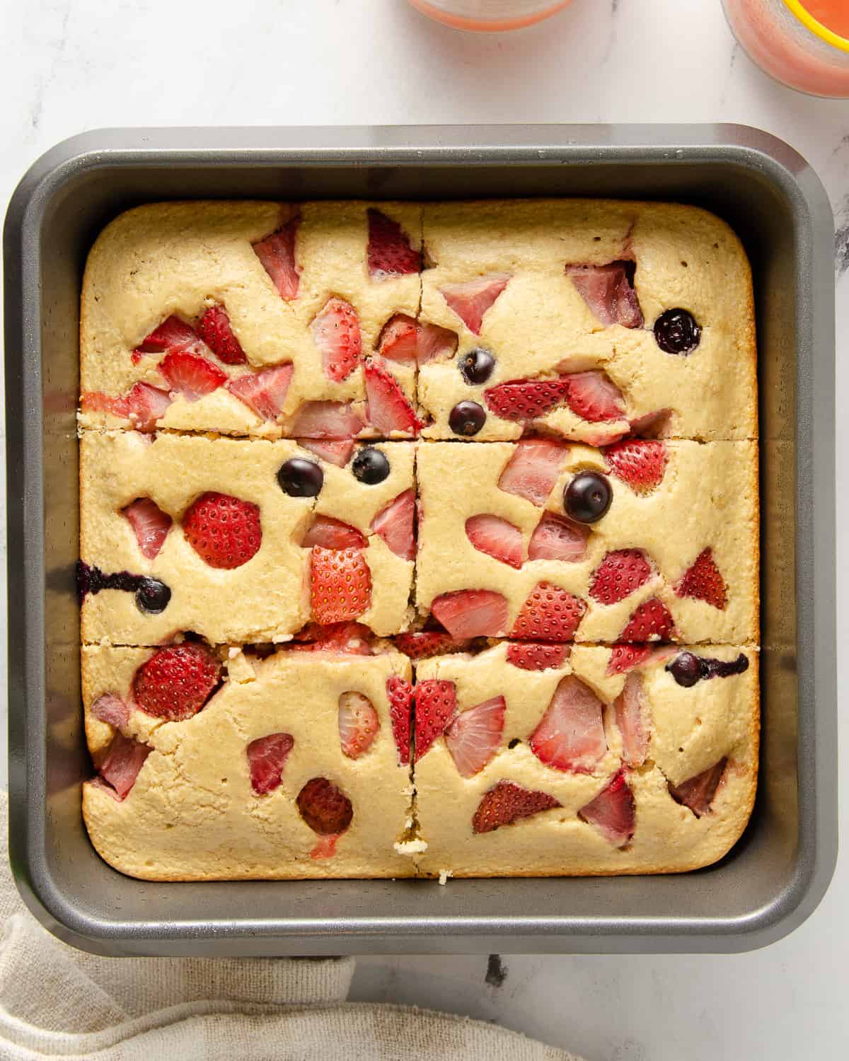Protein baked oats in a baking dish with berries sliced into six pieces.