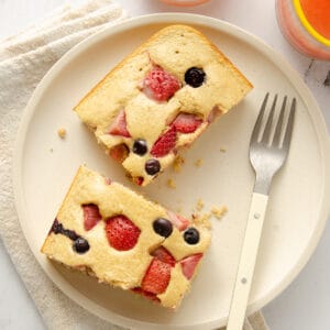 Top down view of two slices of protein baked oats topped with berries on a white plate with a fork.