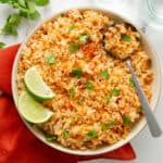 A large bowl of Mexican rice topped with cilantro and fresh lime on top of a napkin.