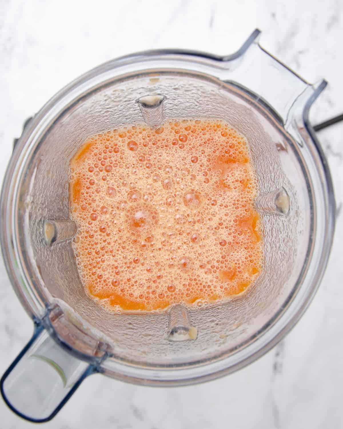 Blended tomato, onion, and vegetable broth in a blender.