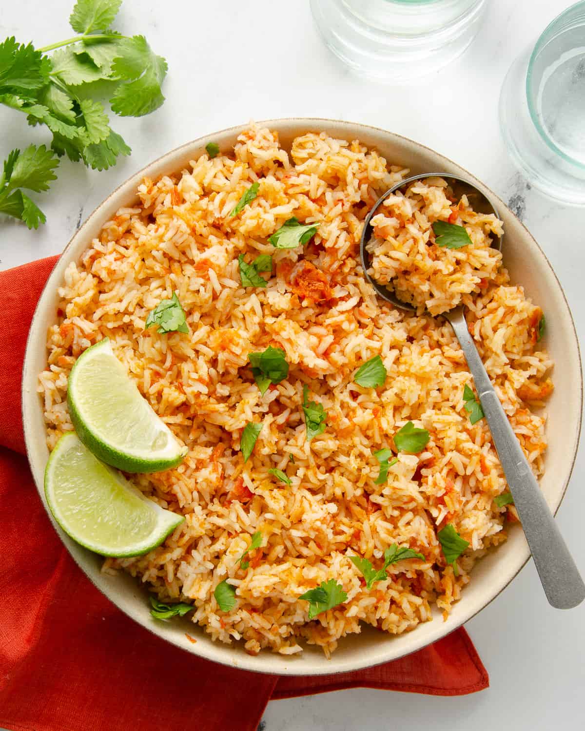 A large bowl of Mexican rice topped with cilantro and fresh lime on top of a napkin.