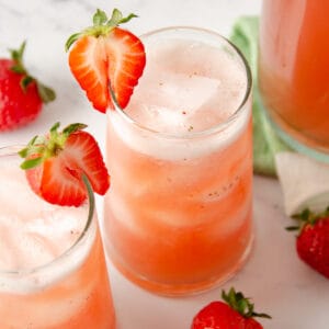 Two glasses of agua de fresa topped with strawberry slices.