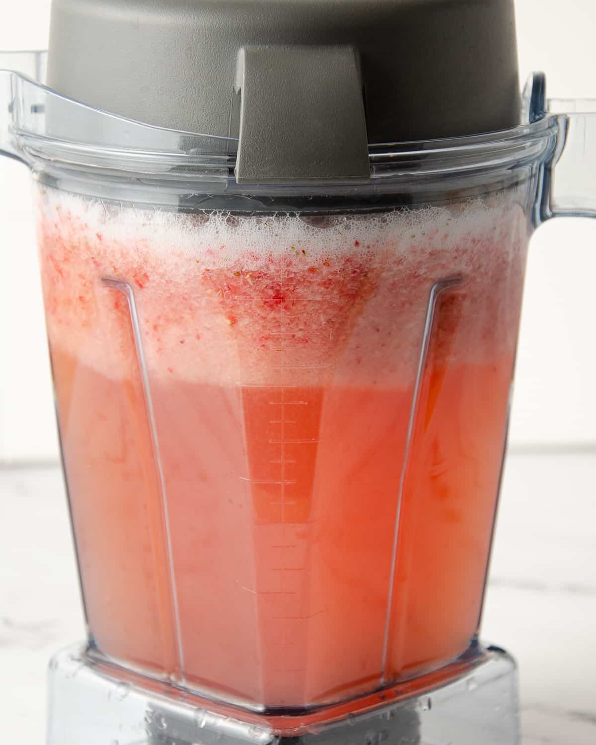 A blender full of blended strawberries and water.