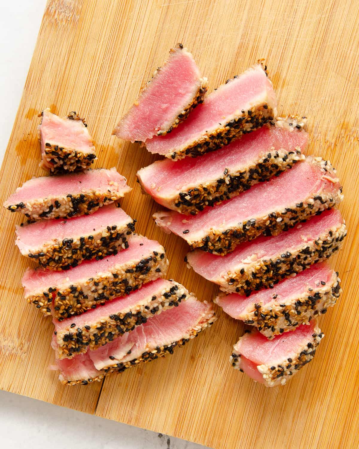 Sesame crusted seared ahi tuna sliced on a cutting board.