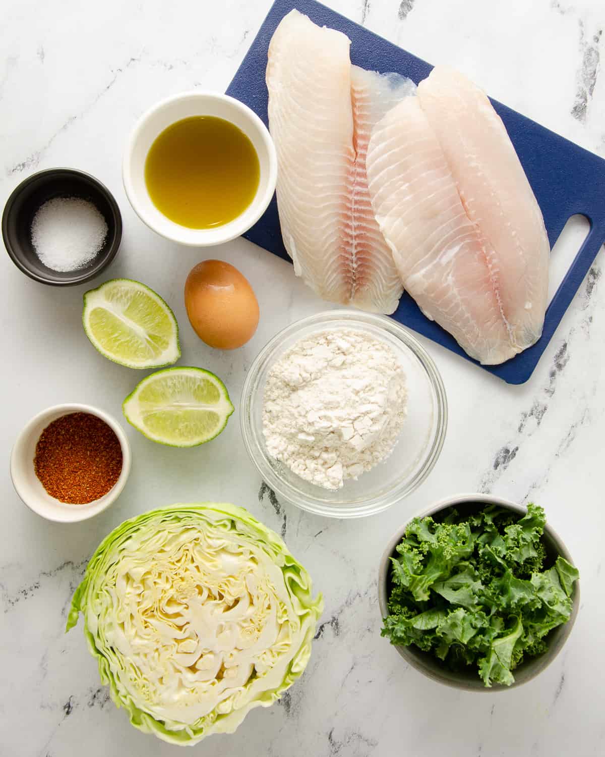 Ingredients needed to make crispy fish tacos on a white countertop.