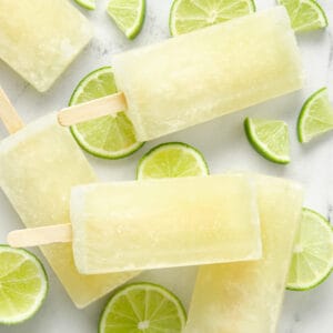 A featured image of lime popsicles and lime wedges on marble.