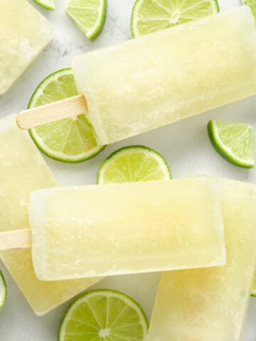 A featured image of lime popsicles and lime wedges on marble.