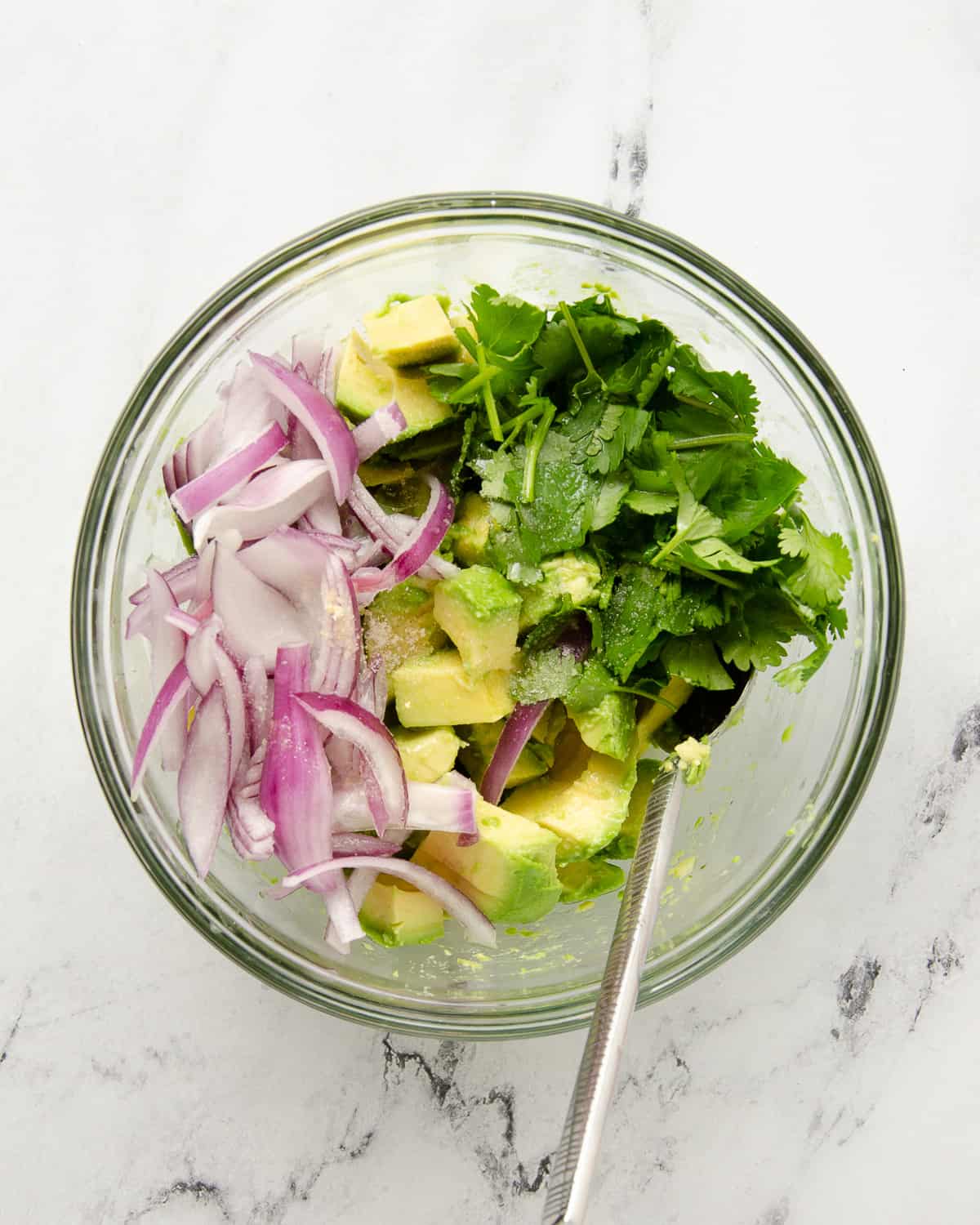 A large bowl of all unstirred ingredients to make an avocado salad.