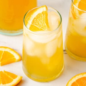 A glass in the center garnished with an orange wedge.