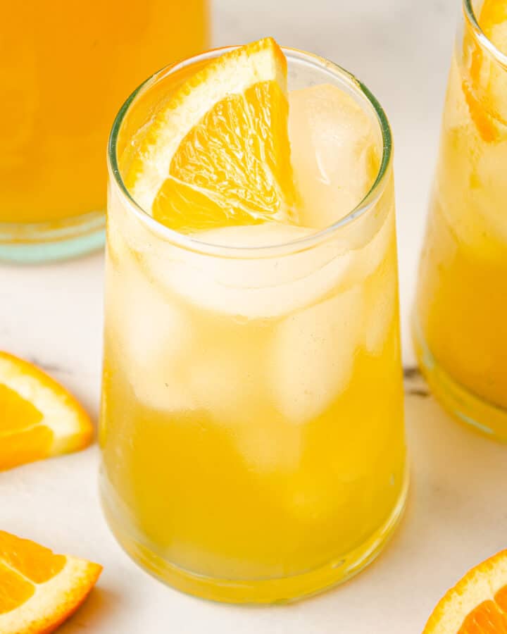 A glass in the center garnished with an orange wedge.