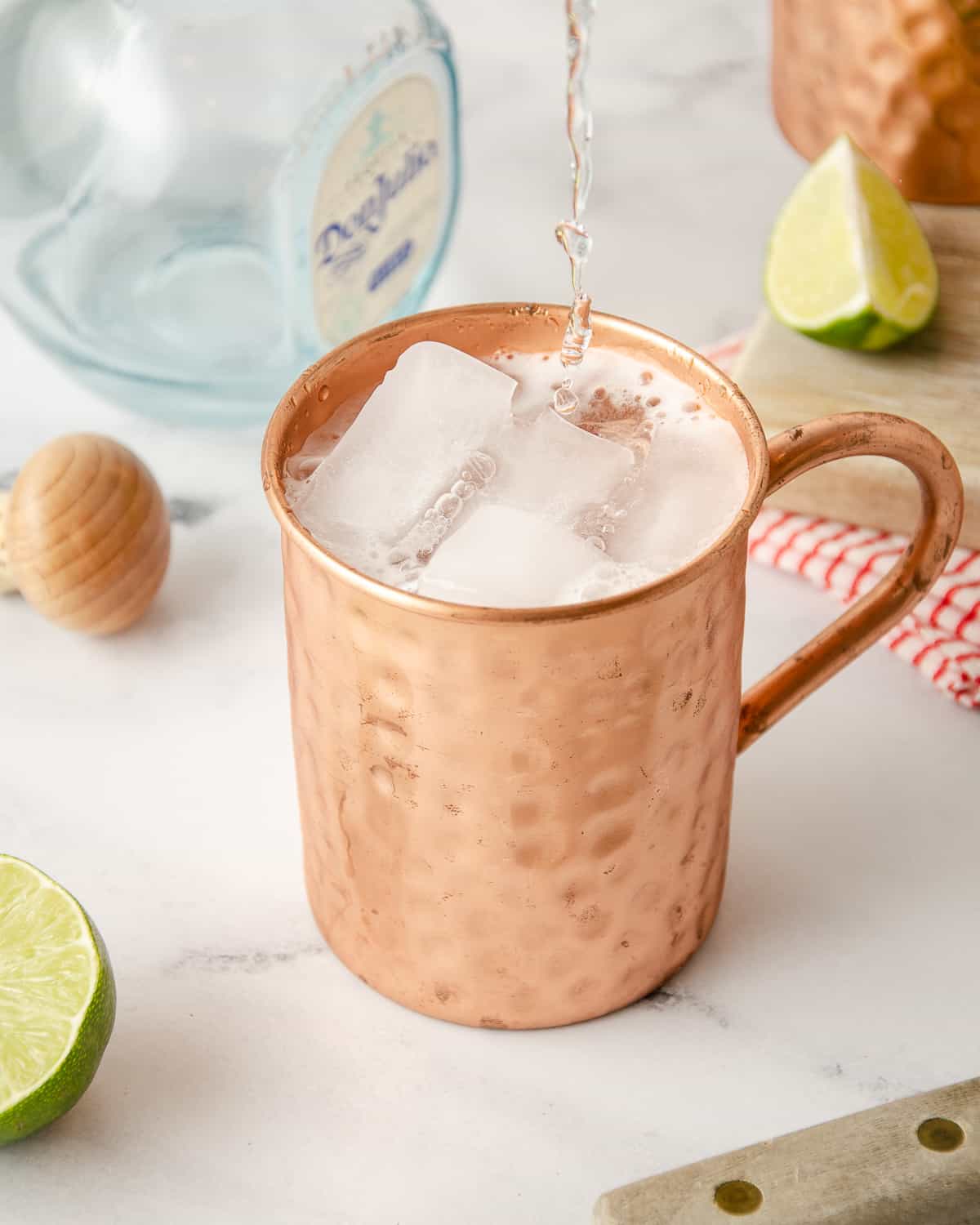 Ginger beer pouring into a copper mug to top of a tequila Moscow mule.