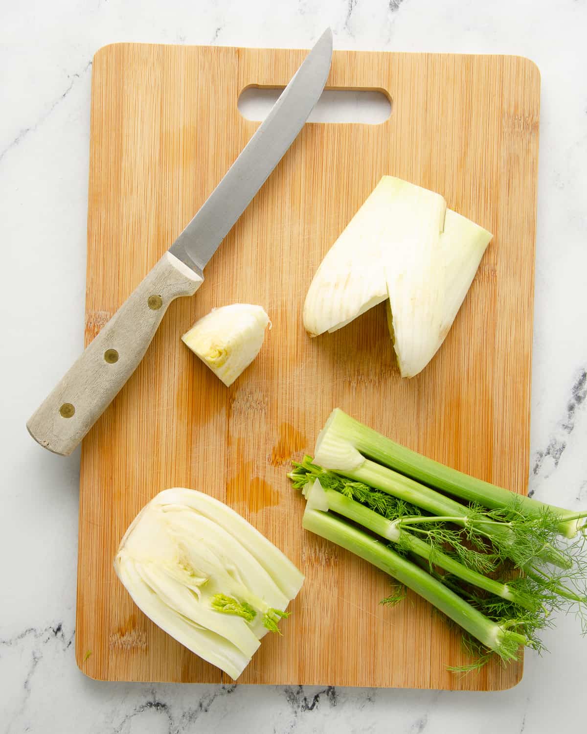 A cutting board with cut fennel and a knife.